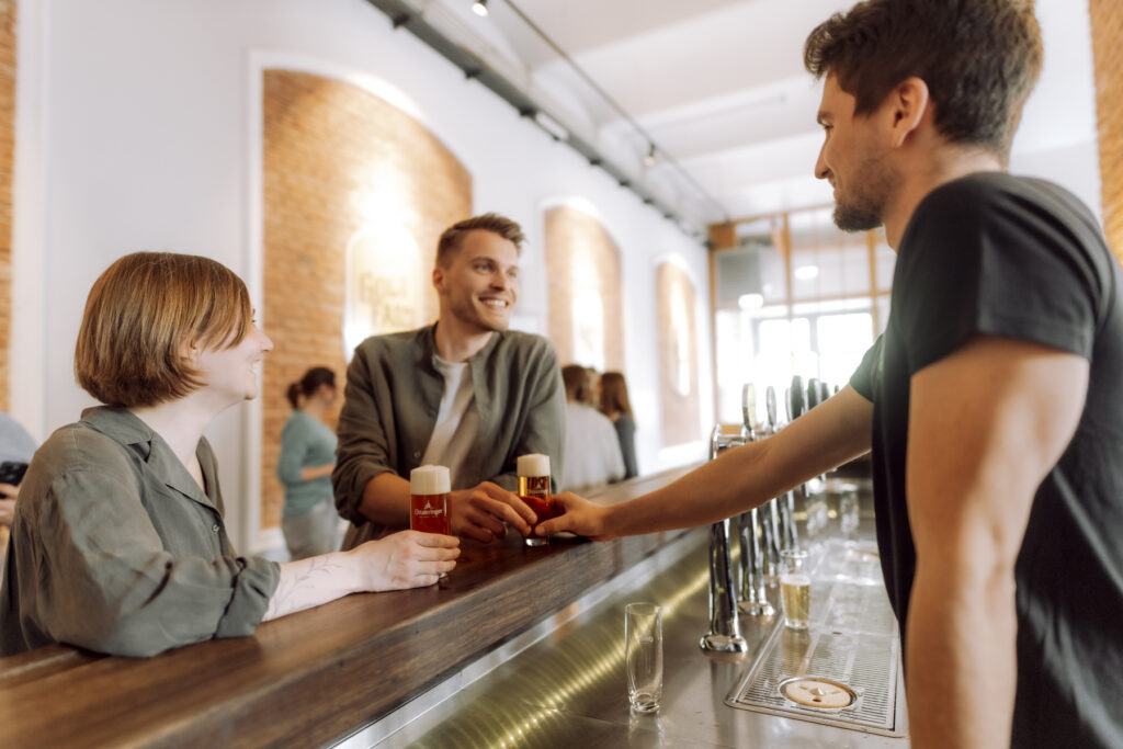 Werbefotografie - Ottakringer Brauerei- eine Gruppe junger Menschen steht an einer Bar und alle trinken Bier und haben Spaß
