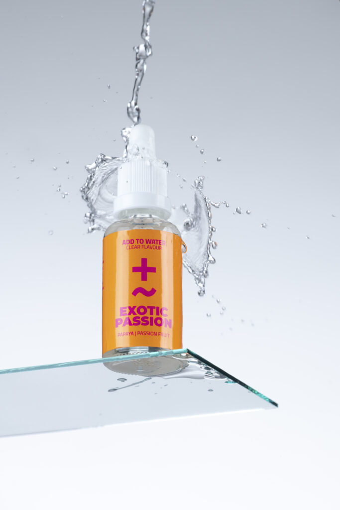 Produktfotografie- ein Fläschchen auf Glasfläche mit Wassertropfen & Wasserspritzer