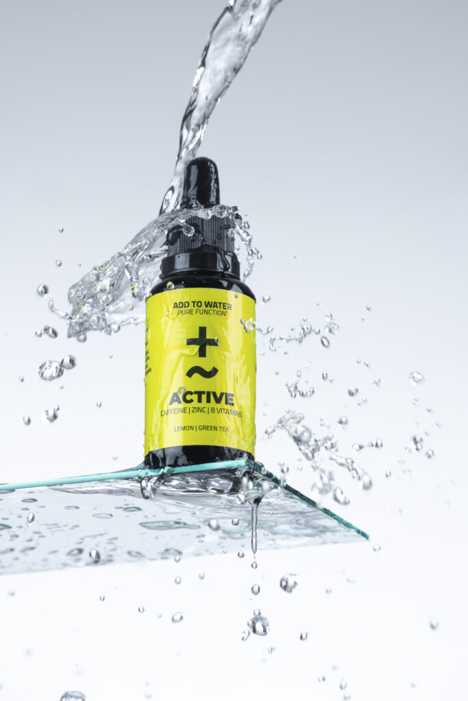 Produktfotografie- ein Fläschchen auf Glasfläche mit Wassertropfen & Wasserspritzer