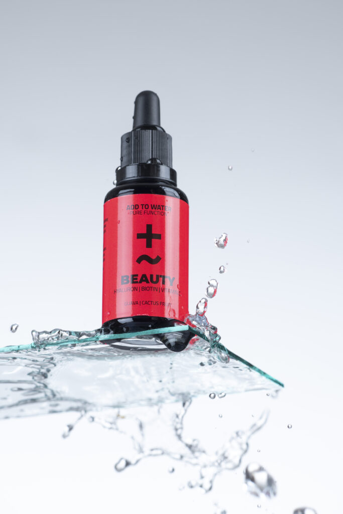 Produktfotografie- ein Fläschchen auf Glasfläche mit Wassertropfen & Wasserspritzer